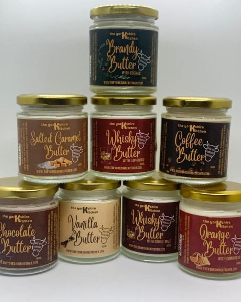 Image of flavoured butter sauces displayed in a 4/3/1 triangle formation, the butters are in glass jars and come in a range of flavours such as whisky, brandy, chocolate and caramel.