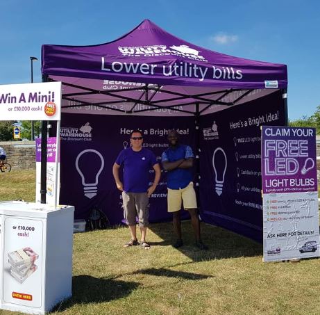 image of purple gazebo with two people standing underneath it , signs outside gazebo saying 'win a mini' and 'free LED lightbulb'