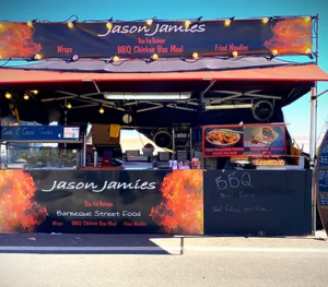 image showing black and orange street food stand selling chargrilled dishes.