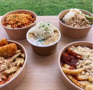 image of 5 crumble dishes in cardboard bowls on a wooden table. dishes imvlude a crumble topped curry, steak and mash topped crumble.