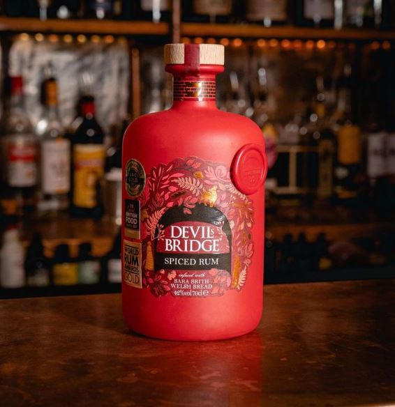 image of bright red coloured rum bottle on bar with other bottles blurred out on shelf in the background