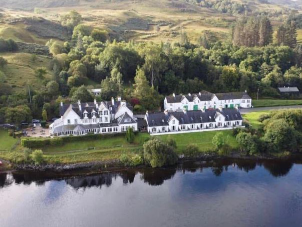 image of beautiful large white hotel and lodges set next to lake and surrounded by beautiful green countryside
