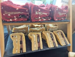 image of different flavour cookie dough pie slices laid out on a two tier slate stand, red velvet pies on the top and oreo pies on the bottom of the stand